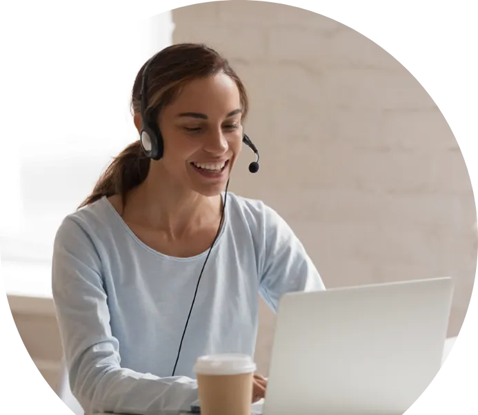 Een lachende vrouw met een headset die op een laptop werkt