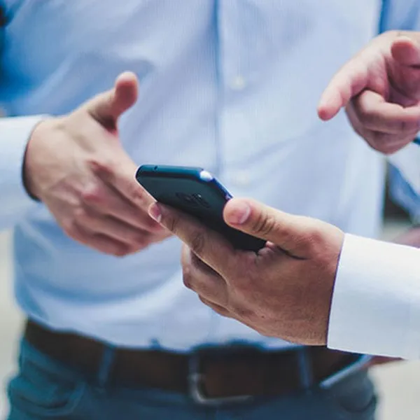 Twee mensen in overhemd die samen naar een smartphone kijken